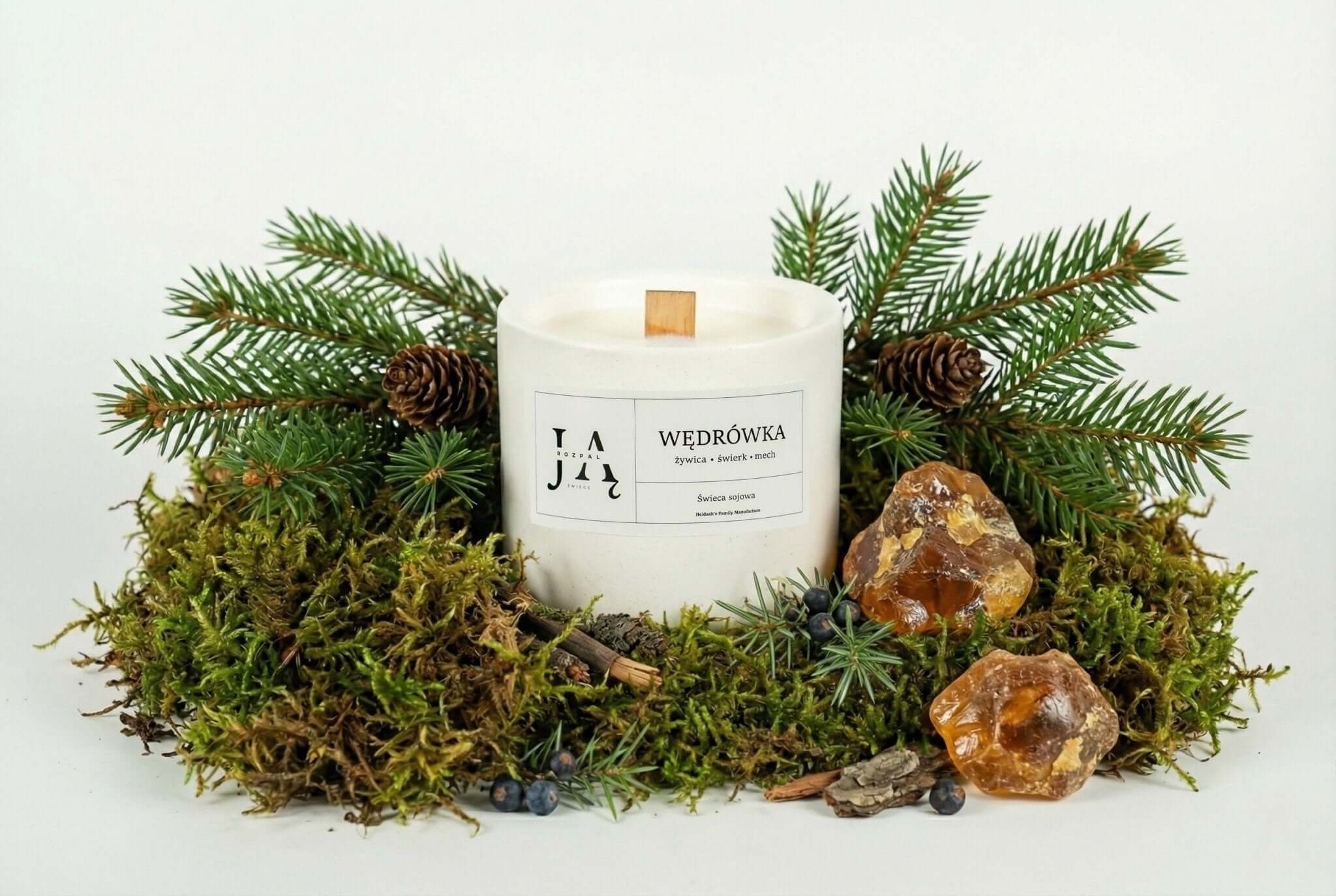 WĘDRÓWKA naturalna świeca sojowa leśna otoczona świeżymi gałązkami drzew, mchem i kamieniami.